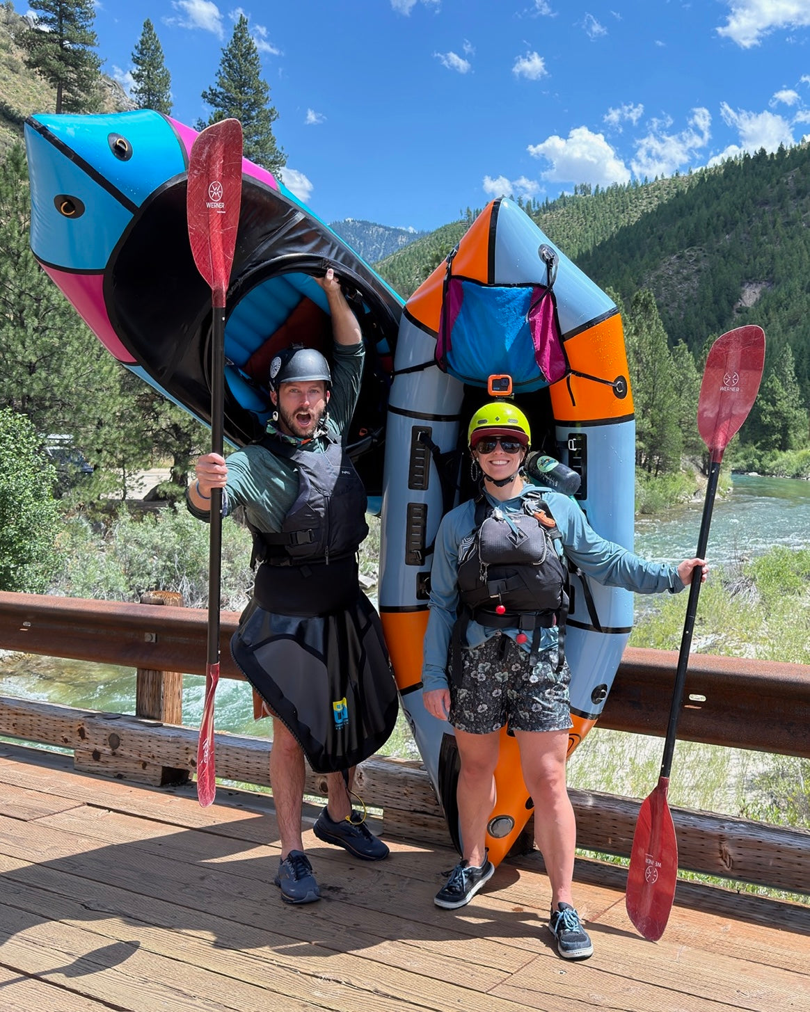 Justin Bickley and Sarah standing with packrafts and paddles beside a river in Idaho