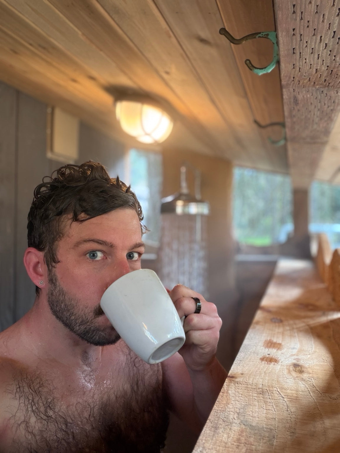 Justin drinking coffee shirtless in a wood sauna