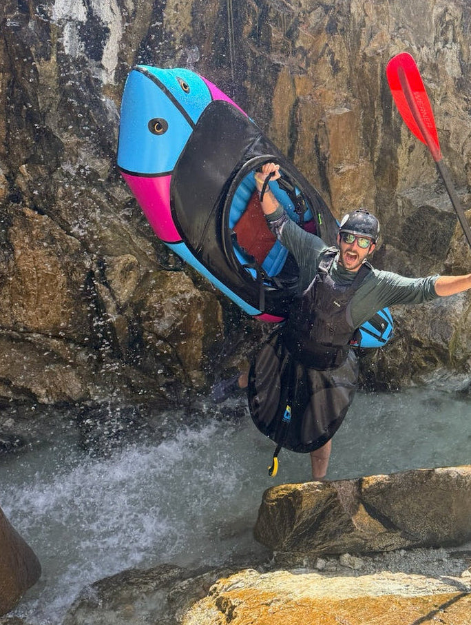 Justin Bickley with a packraft beneath a waterfall